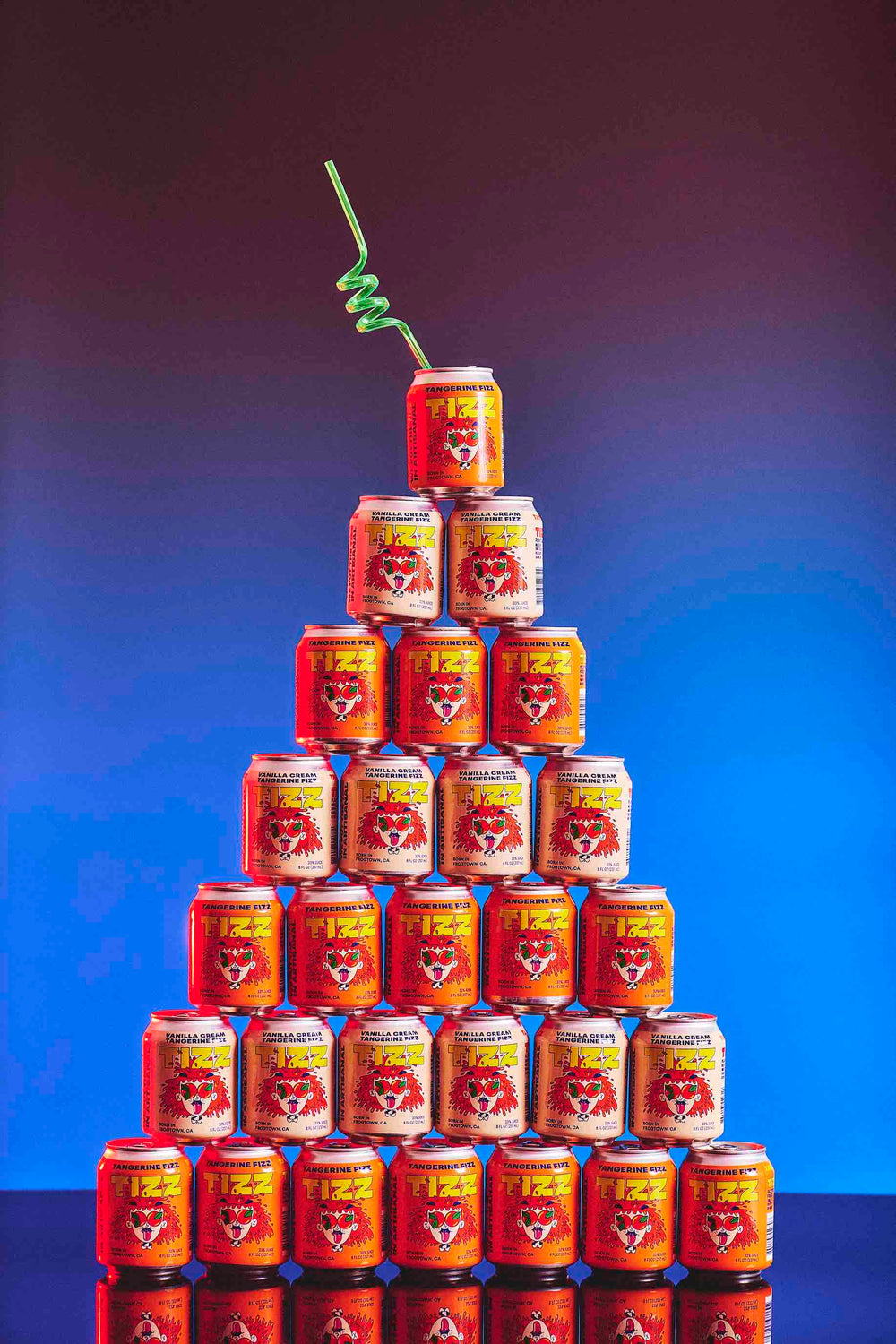 Pyramid of TIZZ Tangerine Fizz and Vanilla Cream cans topped with a green curly straw